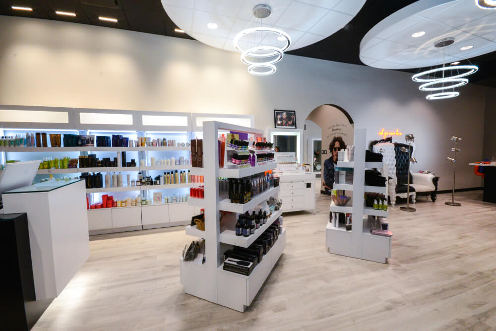 - Studio Wish Salon Spa in Twinsburg, OH Modern bridal beauty salon interior with well-lit shelves displaying hair and beauty products, a stylish reception desk, and salon chairs in the background under circular ceiling lights—perfect for modern hair color services. - Studio Wish Salon Spa in Twinsburg, OH