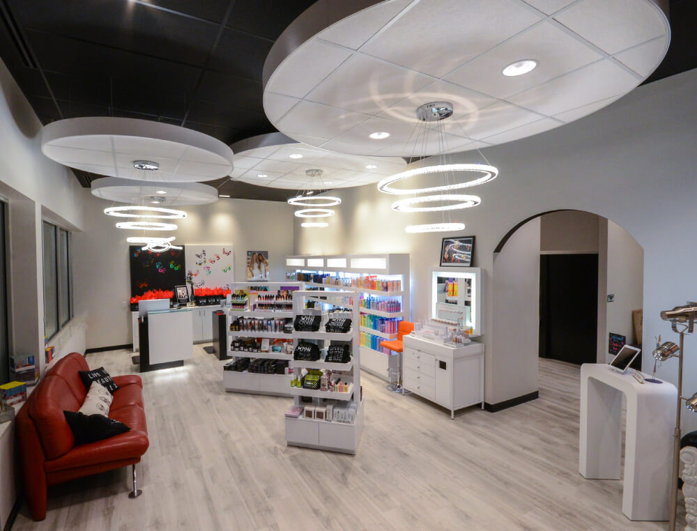 - Studio Wish Salon Spa in Twinsburg, OH Modern salon interior with shelves of beauty products including Aveda, a red couch, bright overhead circular lights, and a reception desk on light wood flooring. - Studio Wish Salon Spa in Twinsburg, OH