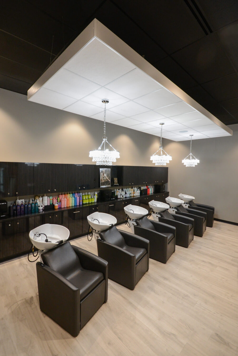- Studio Wish Salon Spa in Twinsburg, OH A modern salon interior with five black shampoo chairs and sinks, chandeliers overhead, shelves of hair products along the back wall, and a dedicated area for bridal beauty salon services and modern hair color treatments. - Studio Wish Salon Spa in Twinsburg, OH